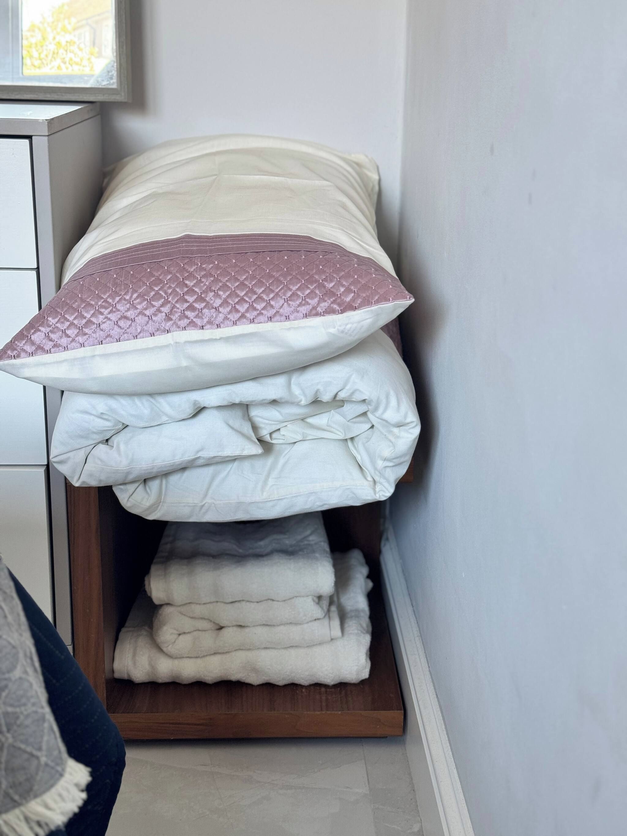 Una cama bien hecha con almohadas y una manta doblada.