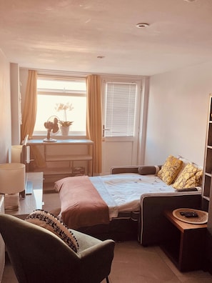 A compact hotel room with a bed, a chair, a desk, and a window with curtains. - Shal Inn at Heathrow Free Parking and Ride on Request (Slough)