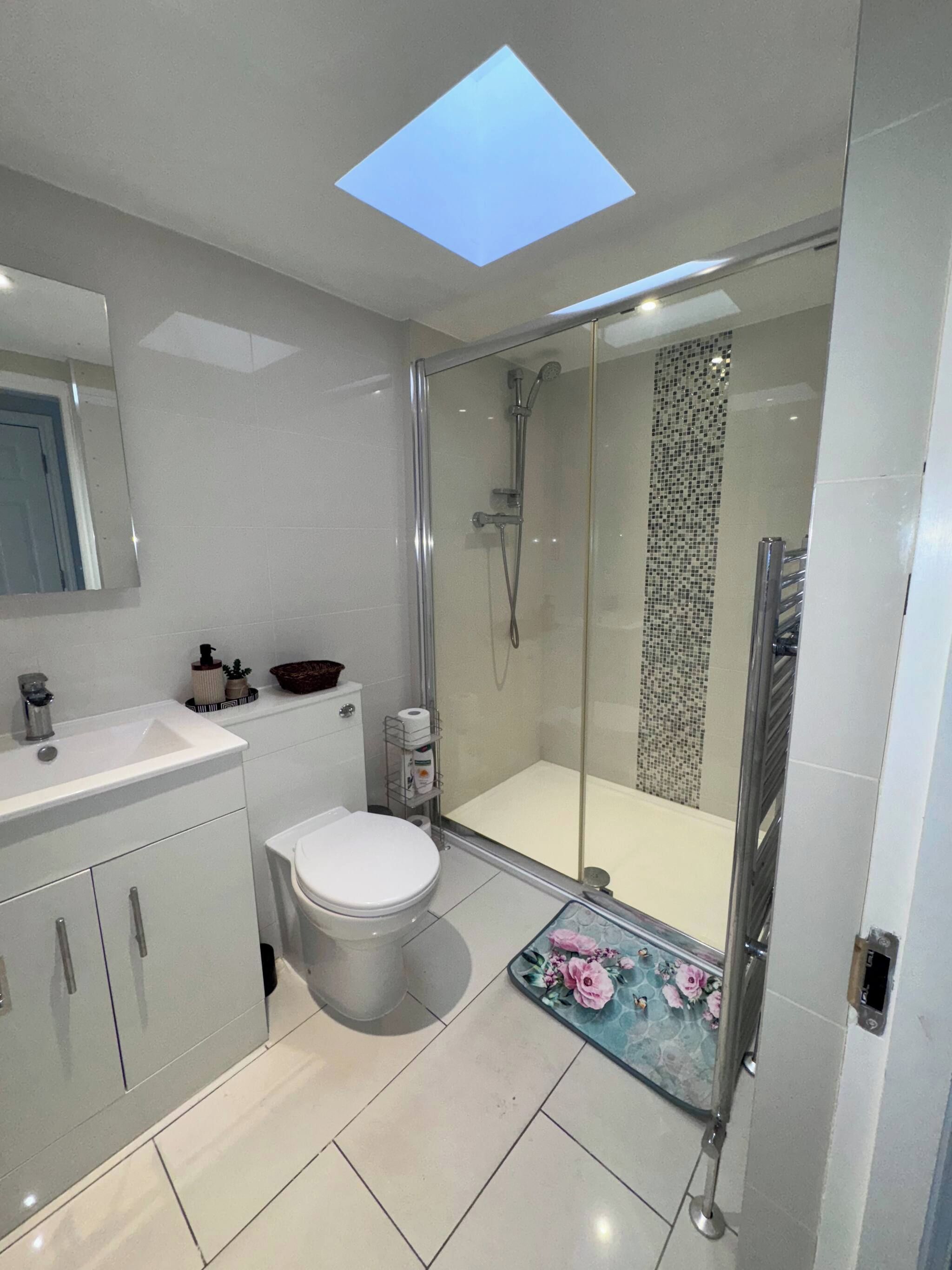 A modern bathroom with a glass shower enclosure, a white toilet, and a vanity with a mirror.