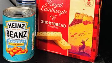 A kitchen counter with a can of Heinz Beanz, a bottle of water, and a box of Paterson's Edinburgh Shortbread Fingers.