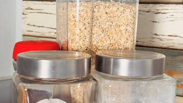 Three glass jars with lids, one containing oats, another with a cloth, and the third with a white powdery substance.