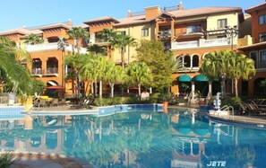 A hotel with a swimming pool surrounded by palm trees and a Mediterranean-style architecture. - 1BR DELUXE sleeps 4- Holiday Get Away 5min to Disney-Wyndham Bonnet Creek Resort (Lake Buena Vista)