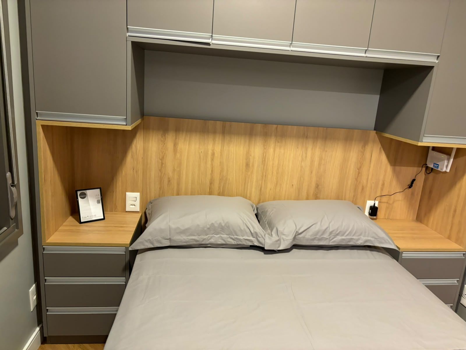 Ein Bett mit einem Holz-Kopfteil, einem Nachttisch und einer Steckdose.