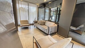 Ein modernes Interieur mit einer Couch, Sesseln und einer Glastrennwand.