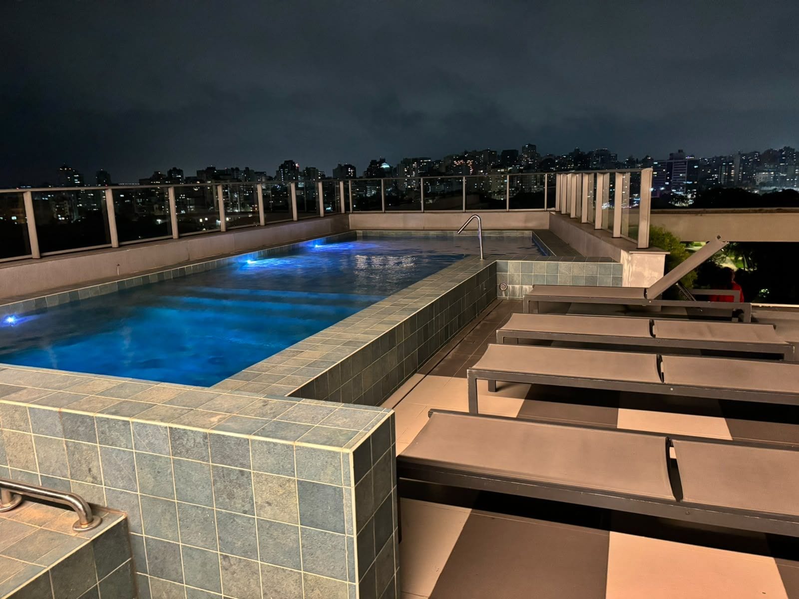 Une piscine sur le toit avec vue sur la ville, de nuit.