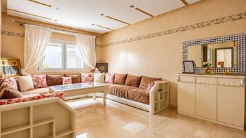 A room with a sofa set, a coffee table, a decorative mirror, and a cabinet.