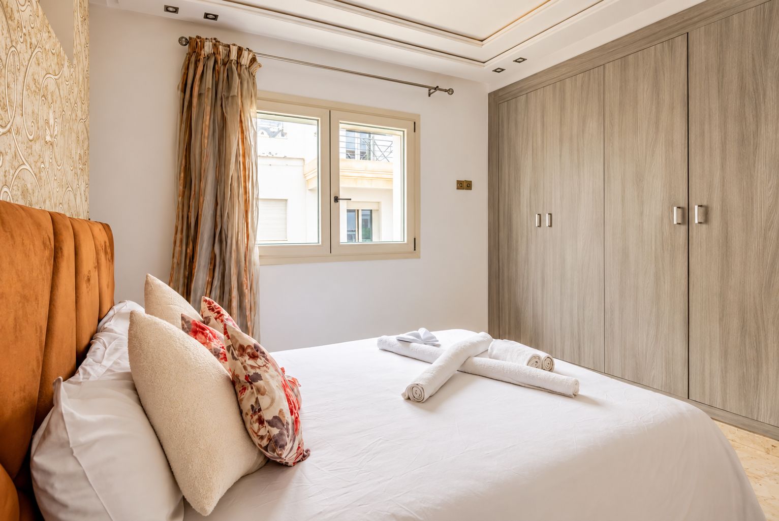Un dormitorio con una cama, almohadas, una ventana y un armario.