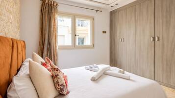 Un dormitorio con una cama, almohadas, una ventana y un armario.