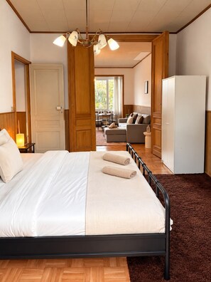 Un dormitorio con una cama, un armario de madera, un escritorio con una lámpara y vistas al exterior.