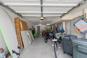 A garage with bicycles, storage bins, and various items on shelves. - Near Beach 4BR OCNJ Retreat / Rooftop Deck & Garage (Ocean City)