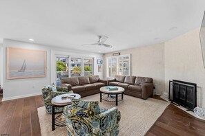 A modern living room with a brown leather sofa, patterned armchairs, a round coffee table, and a fireplace. - Near Beach 4BR OCNJ Retreat / Rooftop Deck & Garage (Ocean City)