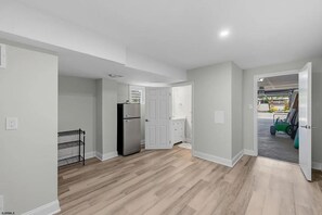 A spacious room with a kitchen area, a door leading to a garage, and a white door to the right. - Near Beach 4BR OCNJ Retreat / Rooftop Deck & Garage (Ocean City)