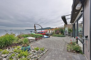 A paved patio with kayaks and a potted plant. - The Beachcomber Suite (Victoria)