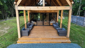 Un espace extérieur aménagé, abrité et doté de meubles en osier et d’une terrasse en bois.