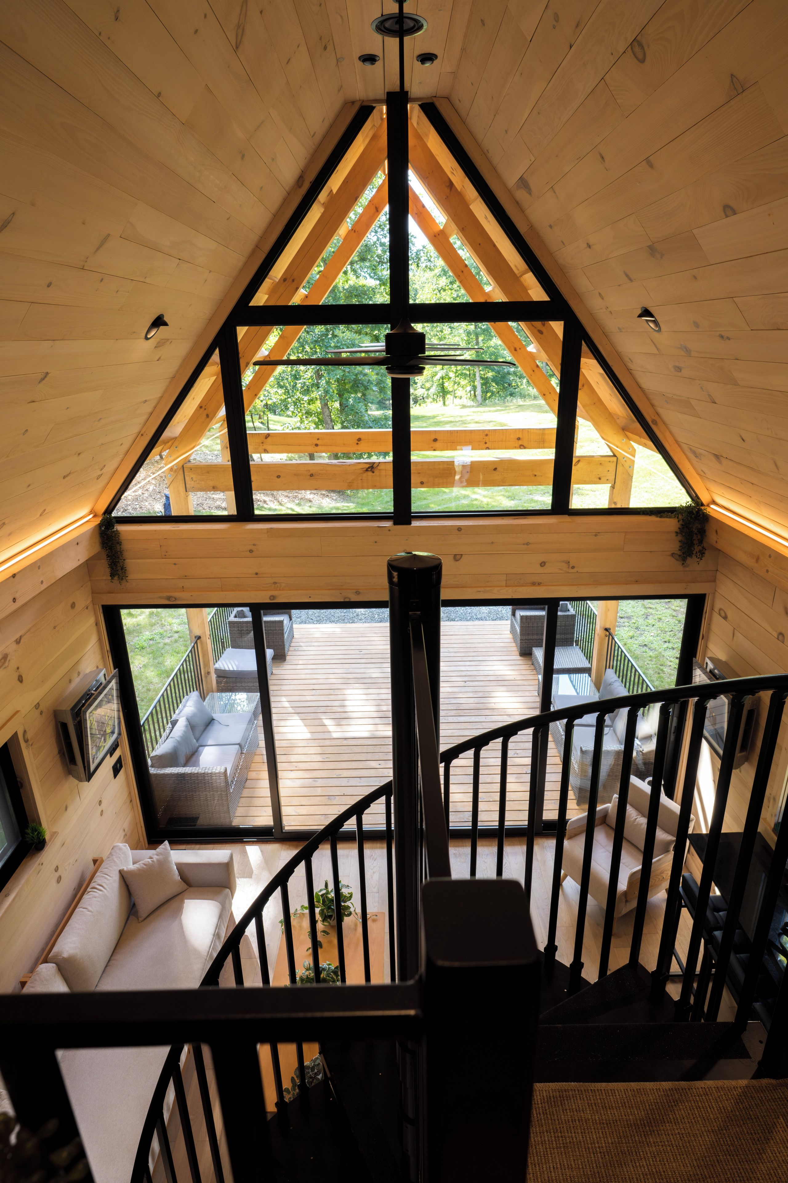 Een houten interieur met een balkon, een trap en een zithoek met kussens.
