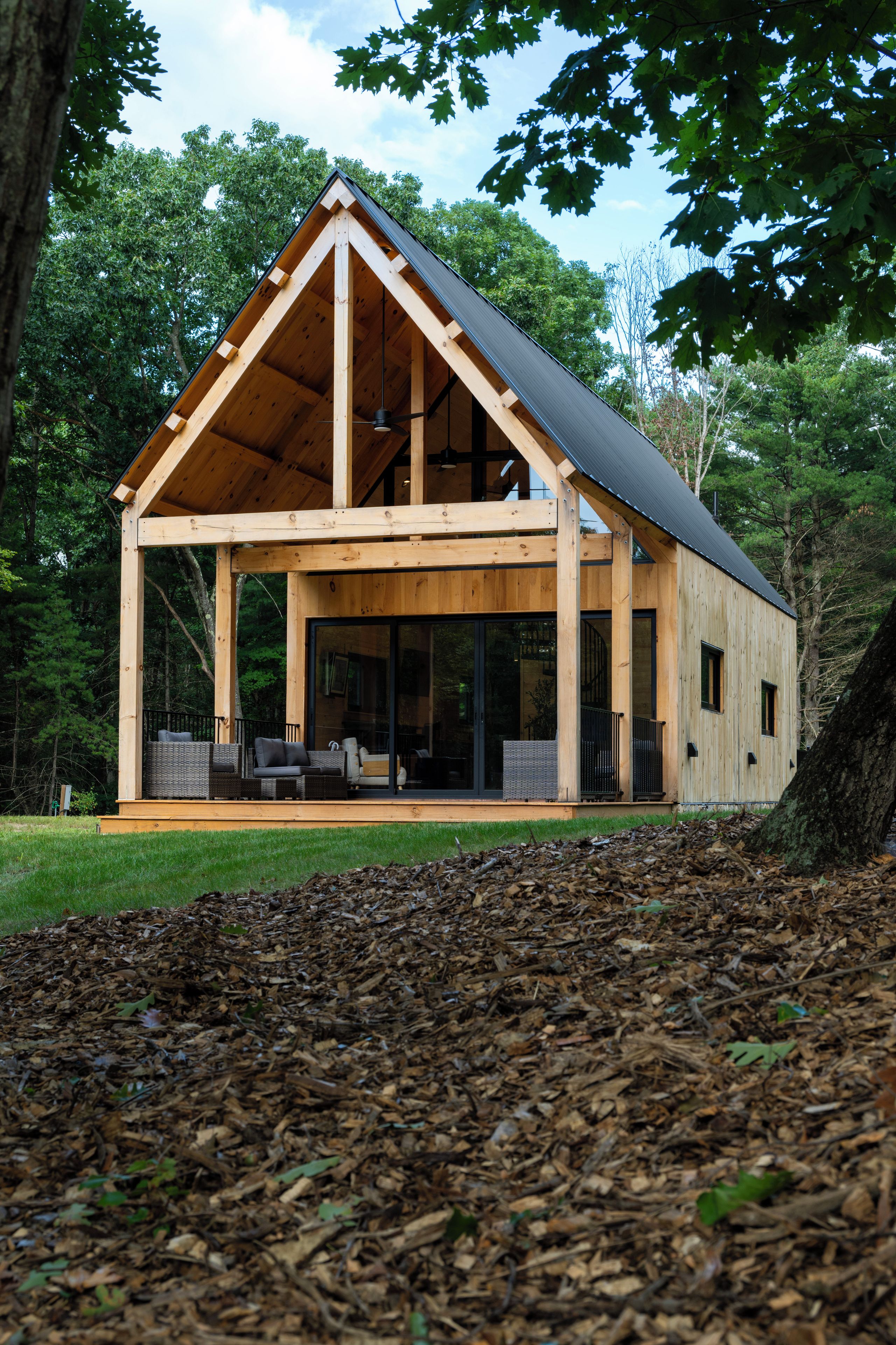 Een moderne houten cabin met een ruime veranda, ingebouwde zitplaatsen en een glazen deur.