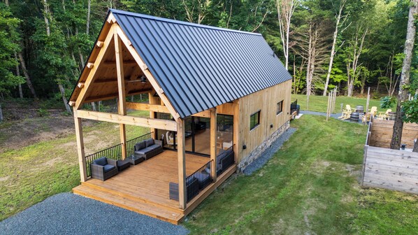 Una cabaña de madera con terraza cubierta y zona de estar al aire libre.