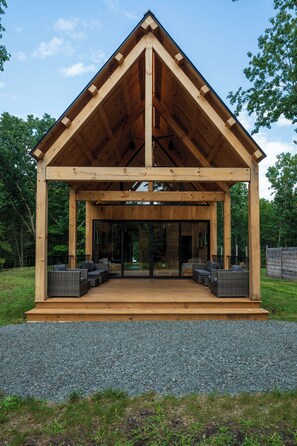 Un espacio al aire libre techado con estructura de madera, asientos y piso de grava.