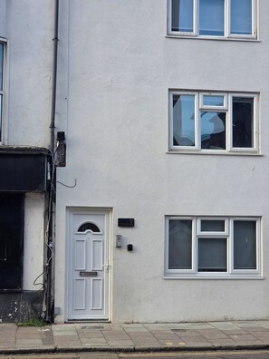 A multi-story residential building with a white exterior, a front door with a number plate, and multiple windows. - Stylish Stay in Brighton London Road Gem (Brighton)