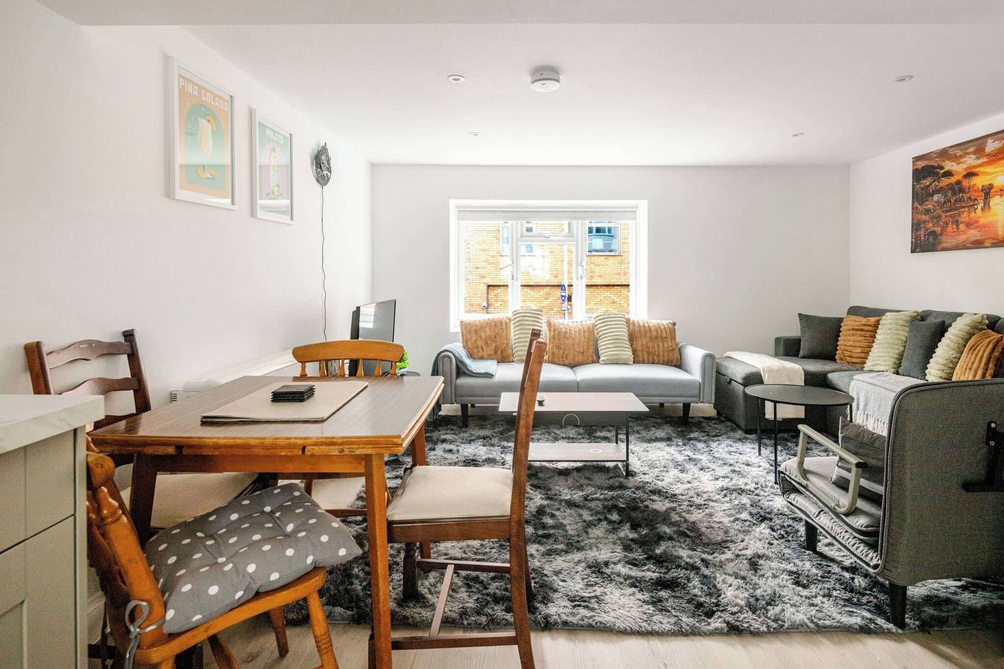 Een moderne woonkamer met een eethoek, een zithoek, een salontafel en een vloerkleed.