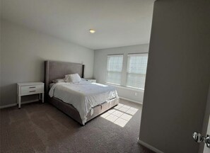 Ein Schlafzimmer mit einem Bett, einem Nachttisch und einem Fenster mit Jalousien.