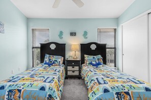 A bedroom with two beds, a nightstand, a lamp, and a ceiling fan. - Coastal Bokeelia Getaway at Bocilla Island Club! (Bokeelia)