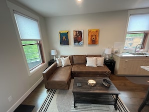 A living room with a brown sectional sofa, a coffee table, and a kitchen area with a sink and countertop. - Ski Winter Park! Cozy Grand Lake Condo ~40 Min to the Slopes (Grand Lake)