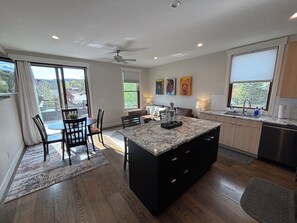 A modern kitchen with a central island, a dining area with chairs, and a view of the outdoors. - Ski Winter Park! Cozy Grand Lake Condo ~40 Min to the Slopes (Grand Lake)