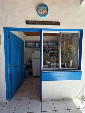 A blue-framed window with a clock above it, a sign above the window, and a door to the left. - Rancho Pura Vida, San Blas Beach, La Libertad, Surf City, El Salvador (Playa San Blas)
