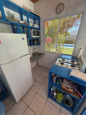 A compact kitchen with a refrigerator, microwave, sink, and stove. - Rancho Pura Vida, San Blas Beach, La Libertad, Surf City, El Salvador (Playa San Blas)