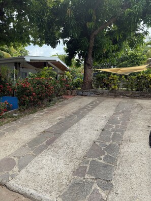 A paved outdoor area with a tree and a house in the background. - Rancho Pura Vida, San Blas Beach, La Libertad, Surf City, El Salvador (Playa San Blas)