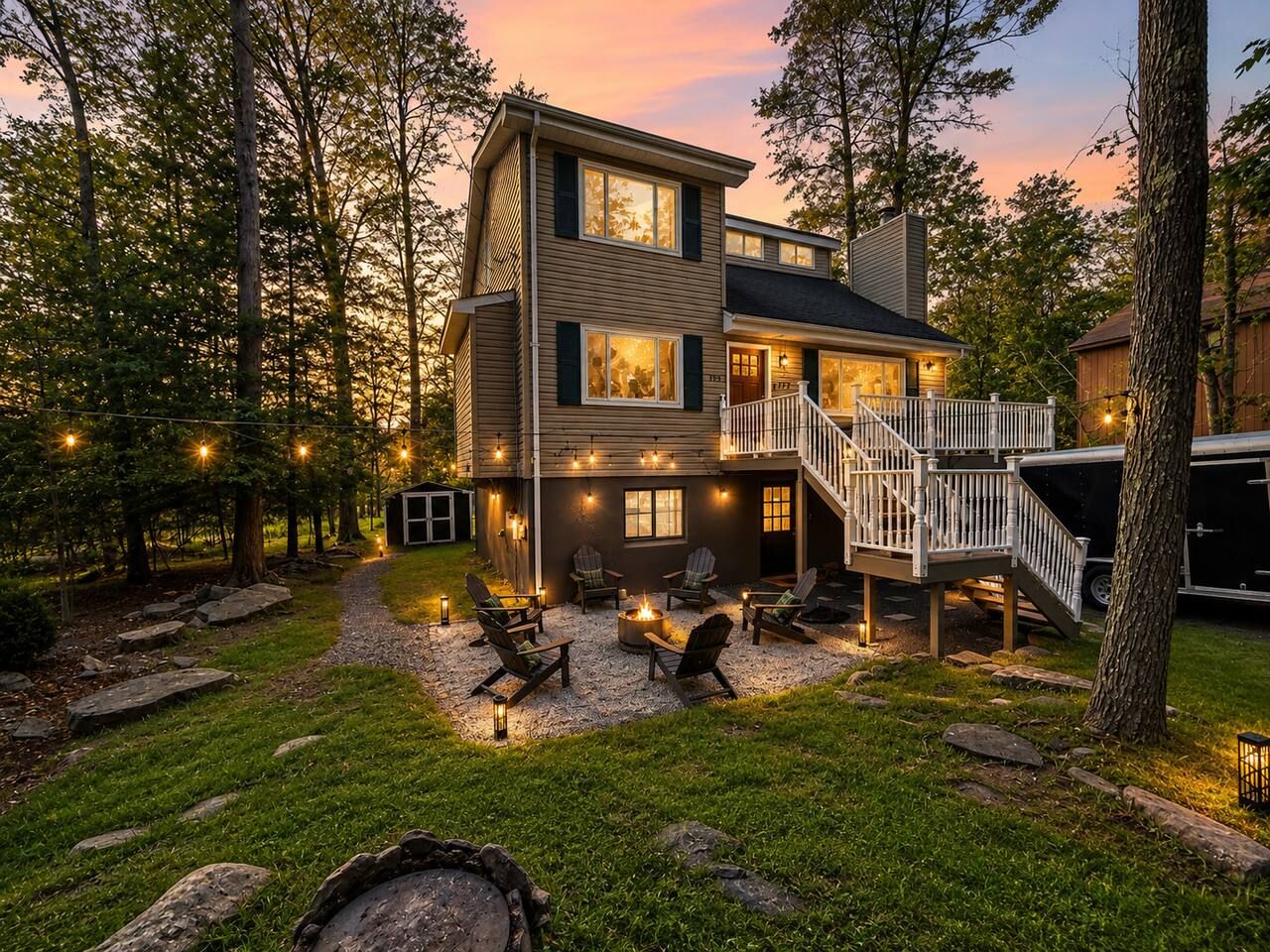 A two-story house with a deck, outdoor seating, and a fire pit.