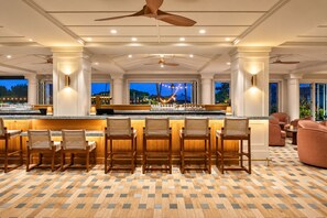 A bar area with multiple seating options, a ceiling fan, and a view of the outdoors. - Kauai Beach Resort Ocean View | Top floor, 2 Beds, 4 Pools & Spa (Lihue)