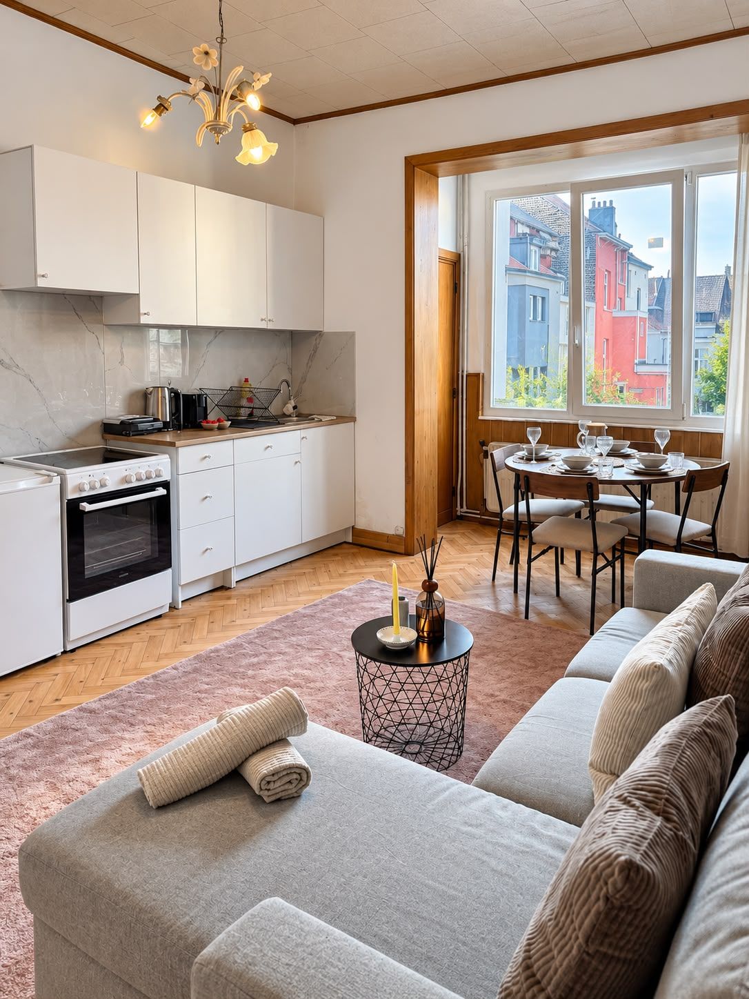 Een moderne keuken met witte kastjes, een fornuis en een eethoek met een tafel en stoelen.