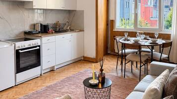 Een moderne keuken met witte kastjes, een fornuis en een eethoek met een tafel en stoelen.