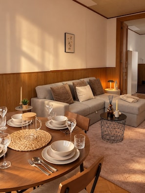 A dining area with a round table set for four, a sofa, and a small side table with a lamp. - Cozy 1BR Retreat in Central Brussels (Bruxelles)