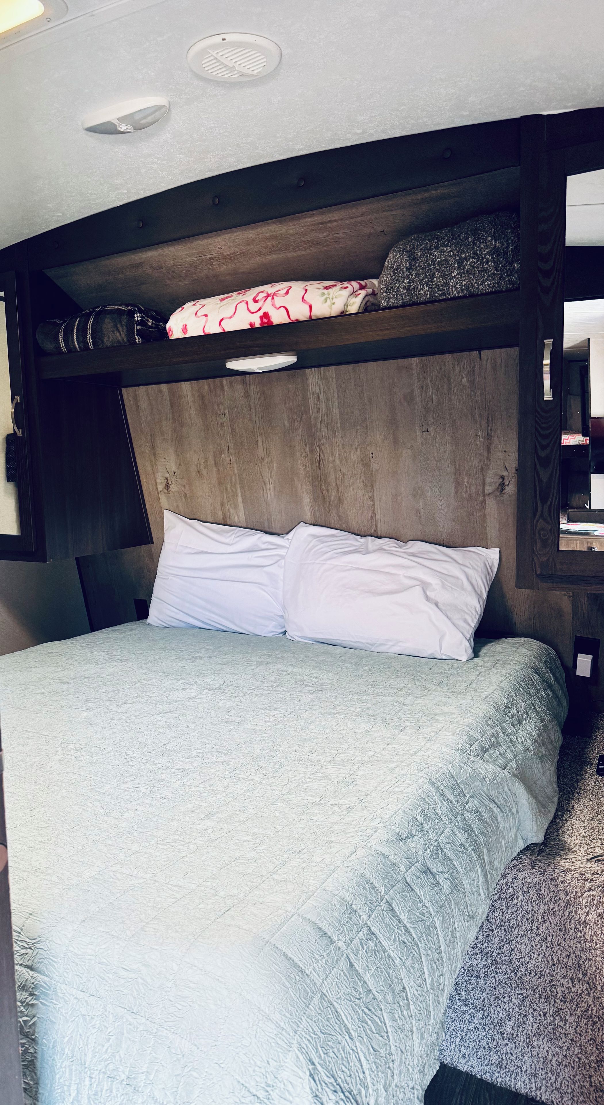 Una cama con cabecera, almohada y manta.