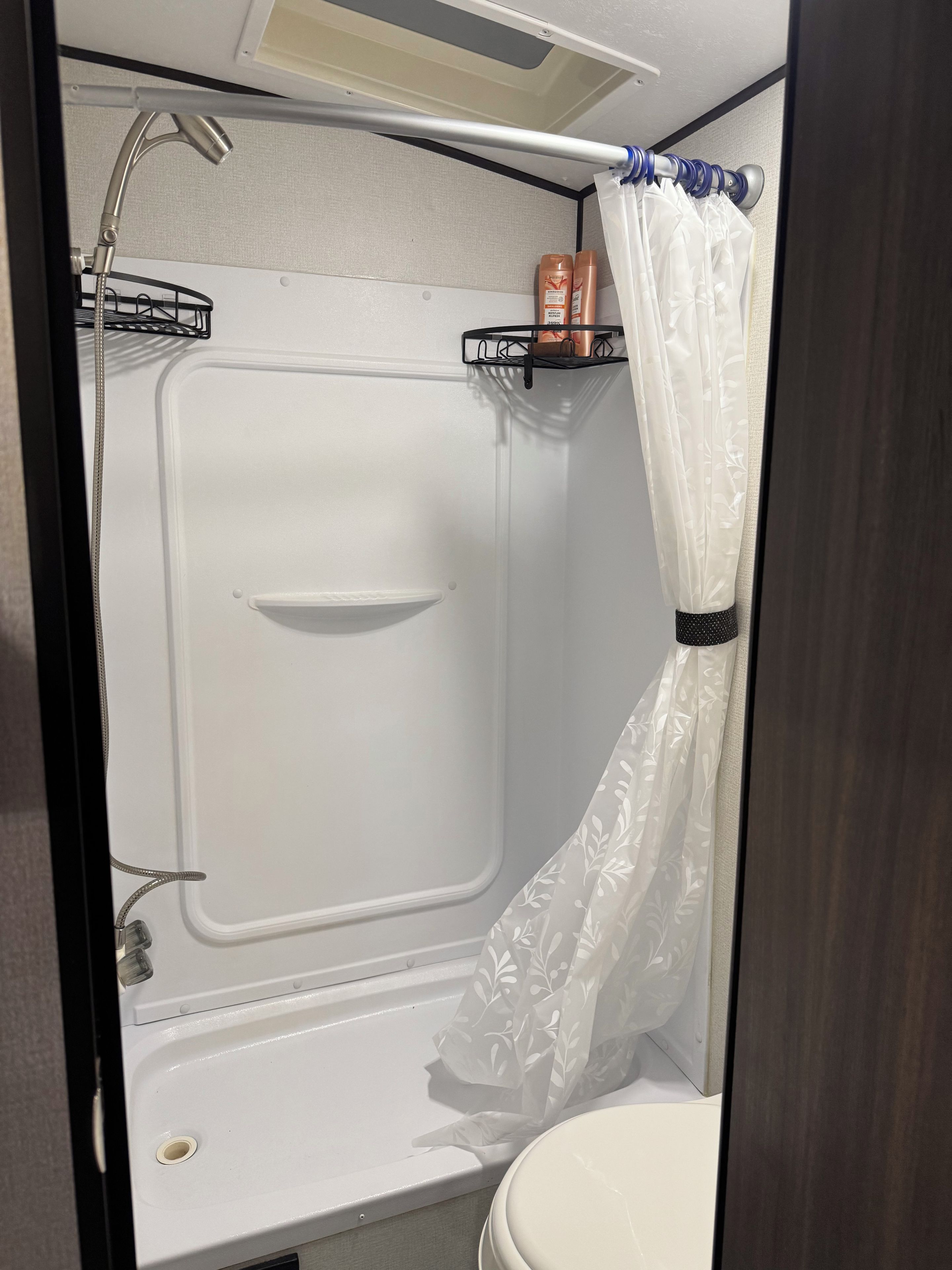 A compact shower area with a white tub, a showerhead, and a curtain.