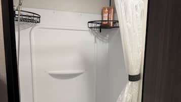 A compact shower area with a white tub, a showerhead, and a curtain.