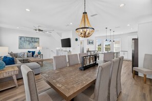 A spacious living area with a dining table, comfortable seating, a chandelier, and a ceiling fan. - Coastal Paradise - Miramar Beach Escape with Pool & Golf Cart (Miramar Beach)