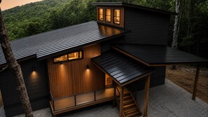 A modern house with a sloped roof, wooden exterior, and a small porch with a staircase. - 2-bedroom house. Altamont TN. (Altamont)