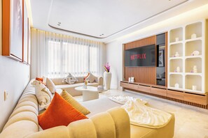 Un salon moderne avec un canapé, une table basse et un téléviseur fixé sur un mur recouvert de panneaux en bois.