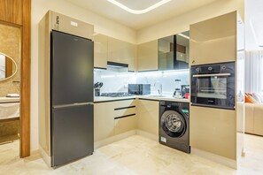 A compact kitchen with a refrigerator, washing machine, oven, and a microwave. - Stylish apartment with a warm atmosphere (Marrakesh)