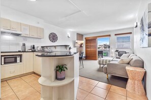 A modern apartment with a kitchen, a living area, and a balcony. - Heart of the City • 1BR with Balcony & Parking (Cairns City)