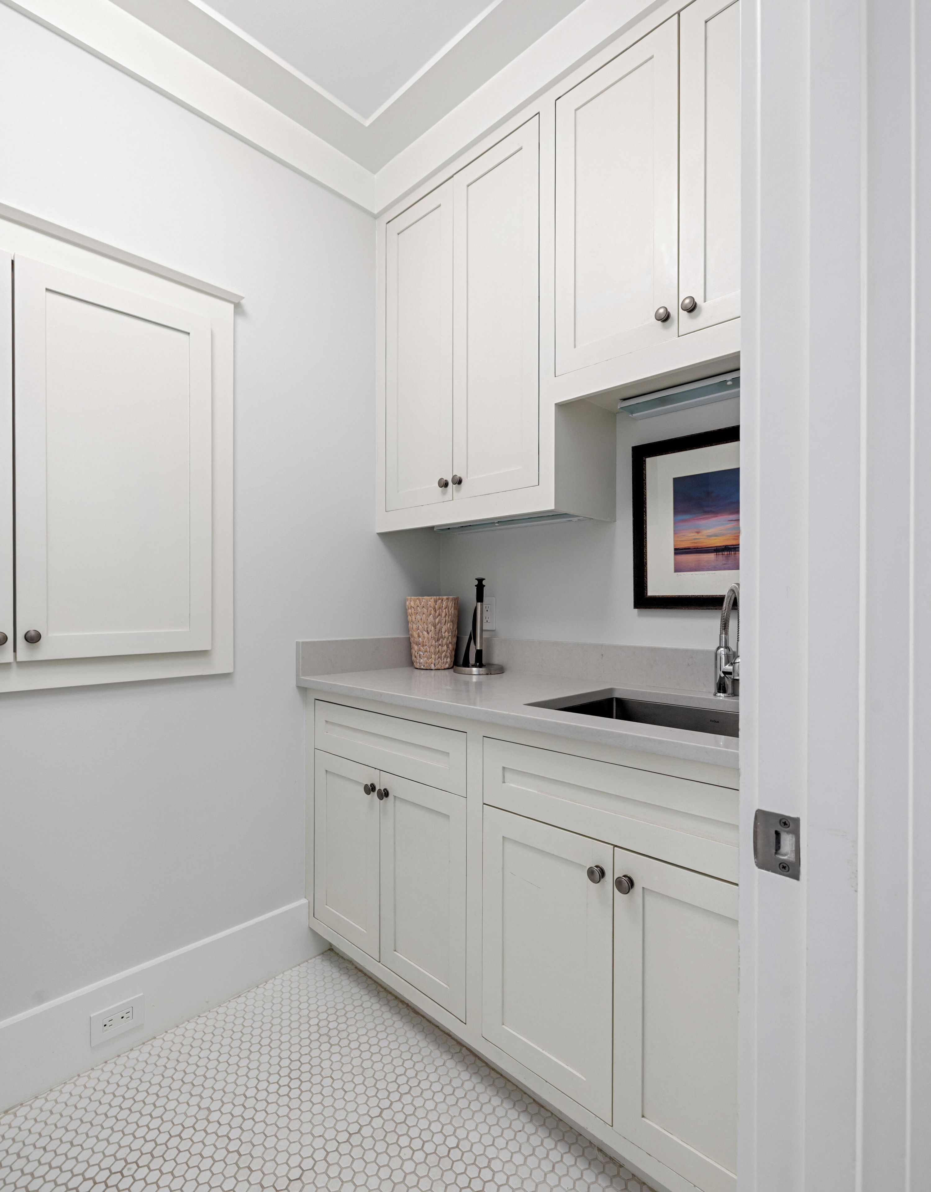 A kitchen with white cabinets, a sink, and a countertop.