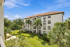 A multi-story building with a tiled roof, surrounded by well-maintained greenery and palm trees. - Stay Central, Explore More, Orlando 3BR Condo (Orlando)