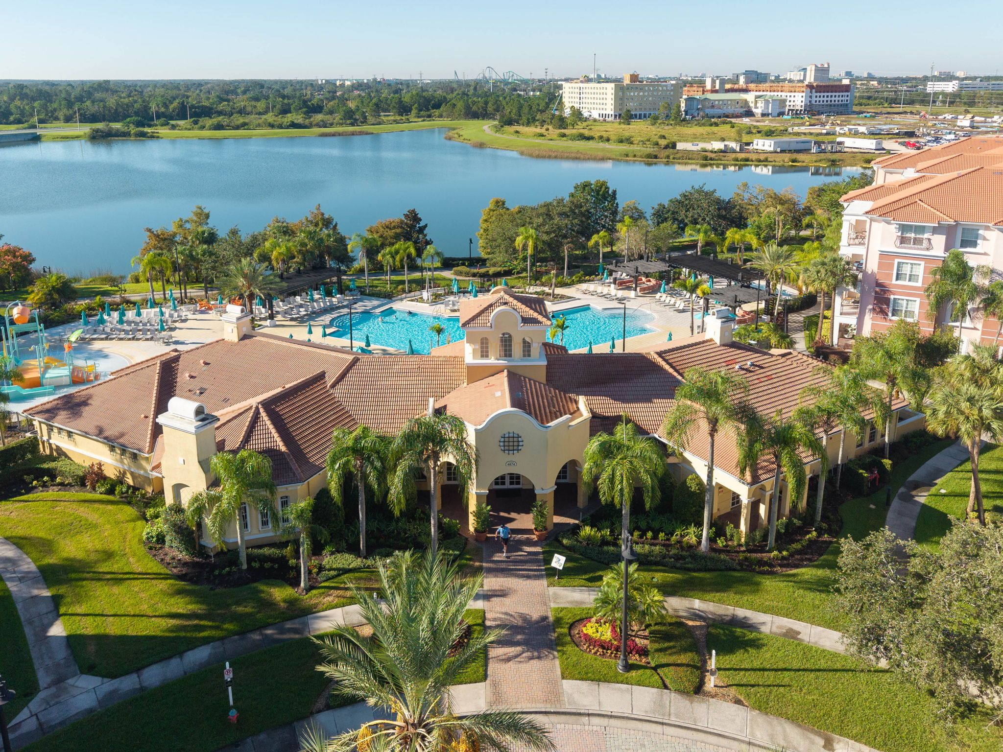 A resort with a swimming pool, palm trees, and a view of a lake.
