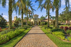 A pathway leading to a building with a symmetrical facade, surrounded by palm trees and well-maintained gardens. - Spacious 3BR in Prime Orlando Location (Orlando)