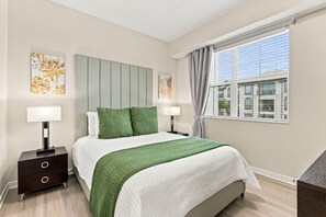 A bedroom with a bed, two bedside tables, a window with curtains, and artwork on the walls. - From Convention Days to Park Days, 3BR Condo (Orlando)