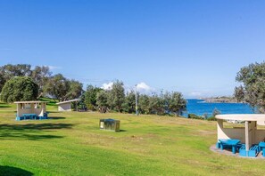 Um parque costeiro com áreas de piquenique e vista para o mar.